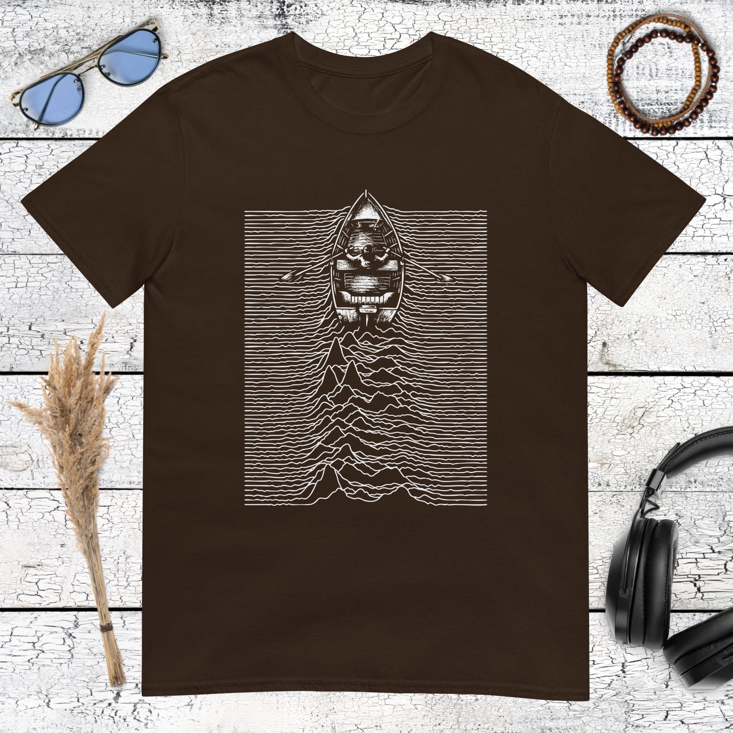 Minimalist ocean boat graphic with abstract waveform lines on a brown t-shirt