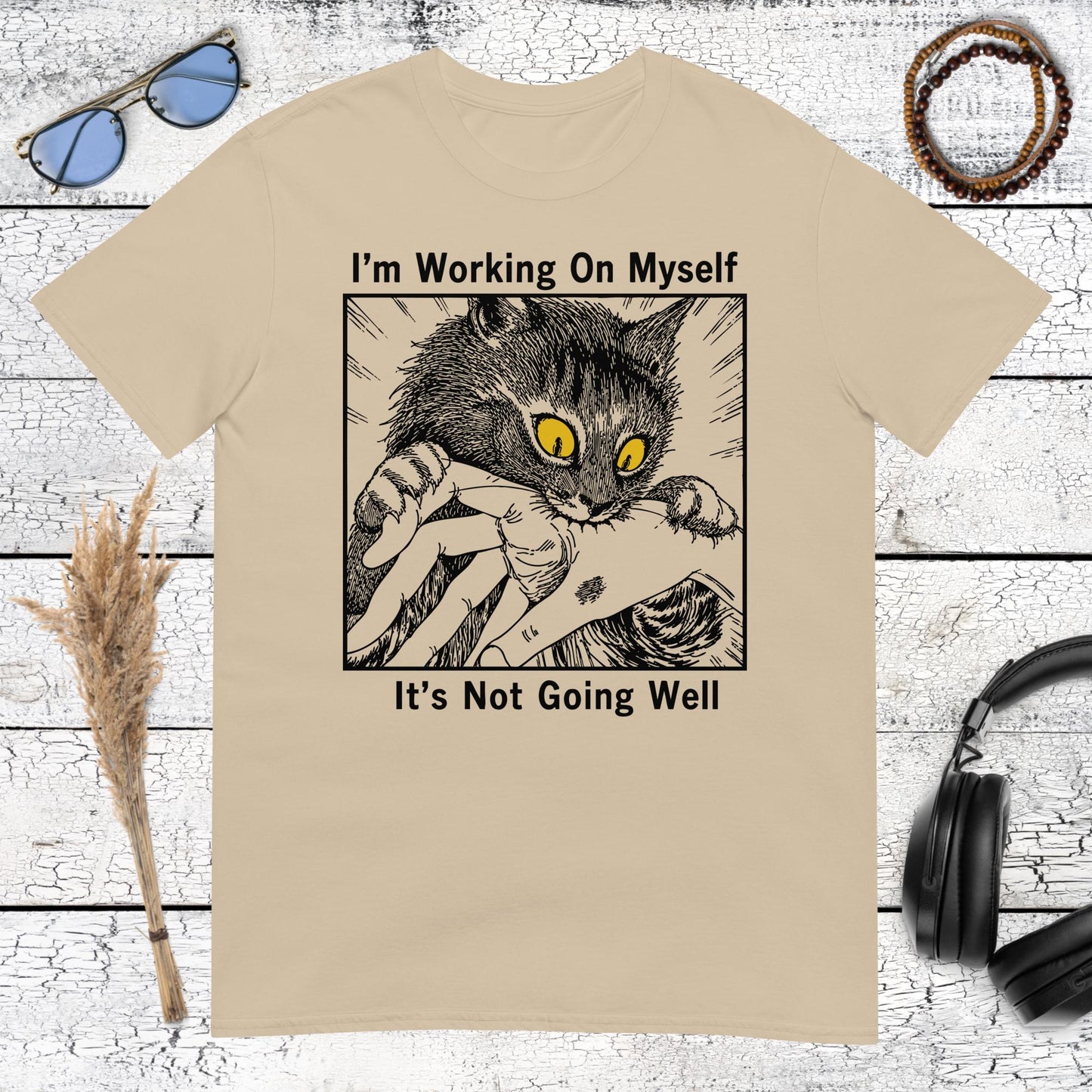 Humorous cat illustration with I’m Working On Myself lettering on a sand t-shirt