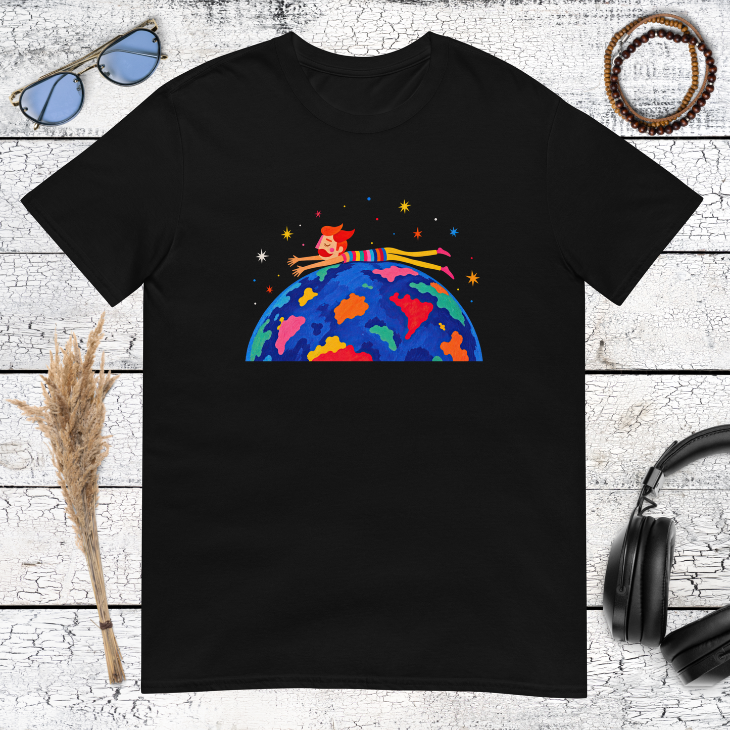 Small human figure riding a colourful Earth in space on a black t-shirt