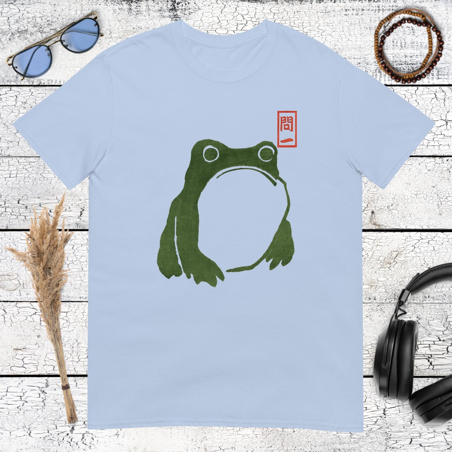 Japanese frog illustration in dark green with red seal detail on a light blue t-shirt